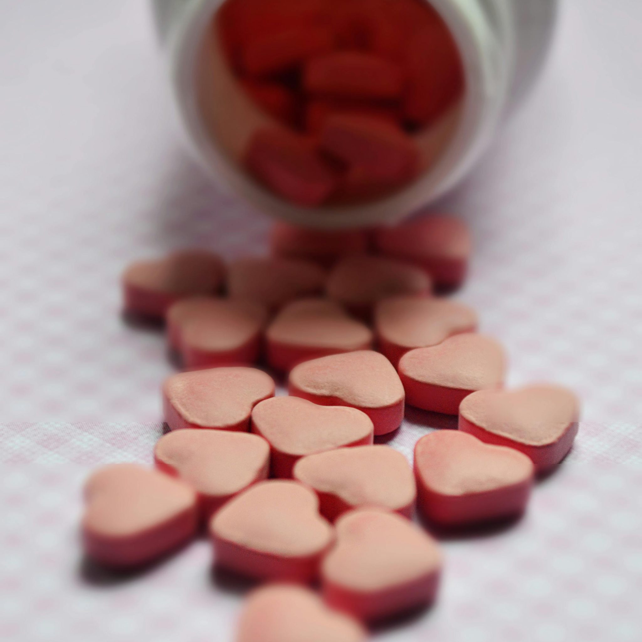 Heart shaped pills spilled on table.
